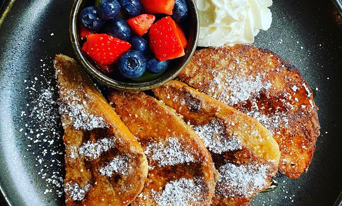 French toast with fruit on a black plate